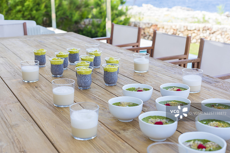 摆放在户外木桌上的绿色思慕雪碗图片素材