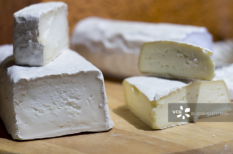 木板上摆放着各种带有白色霉菌外皮的软奶酪块图片素材