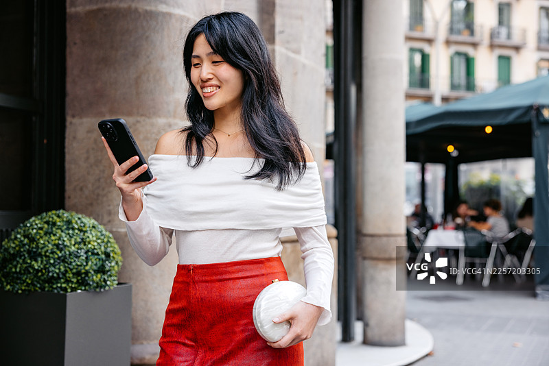 一位年轻的中国女性在西班牙巴塞罗那的街头使用手机图片素材