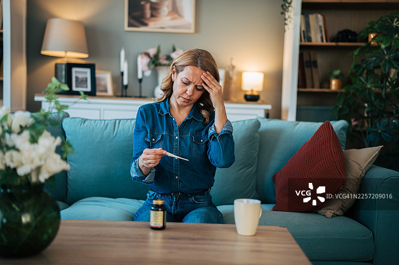 女子正用体温计测量体温，感觉发烧图片素材