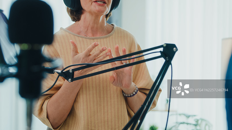 特写镜头：成熟的高加索女性和年轻的拉丁裔女性网红戴着耳机，在家用工作室通过平板电脑与现场观众互动，主持播客节目。直播播客节目和采访。图片素材