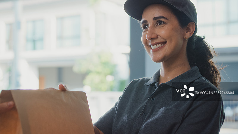 特写：拉丁裔送餐女郎将纸袋递给一位住在房子里的老年高加索男性顾客。快递服务、在线购物或电子商务概念。图片素材