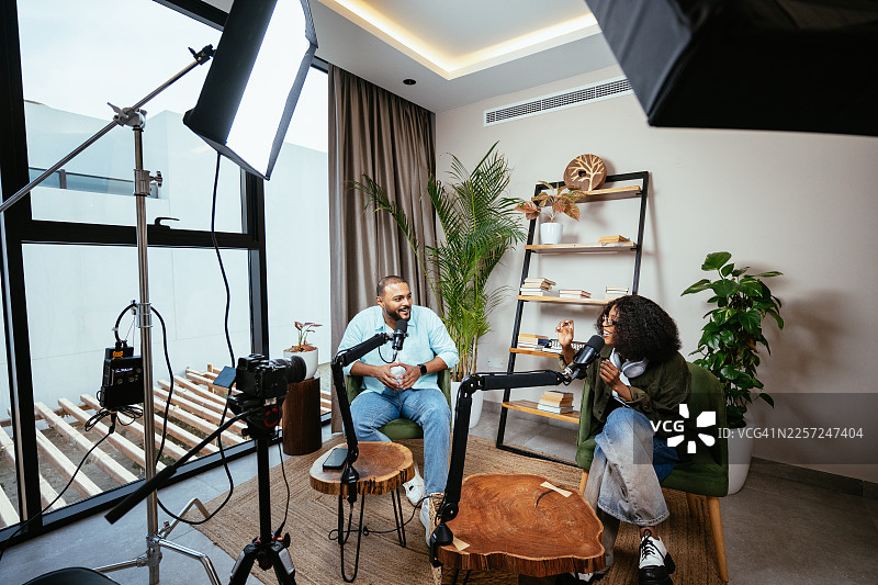 年轻的Z世代多元化网红和视频博主在播客录音棚进行采访和实时直播的广角镜头图片素材
