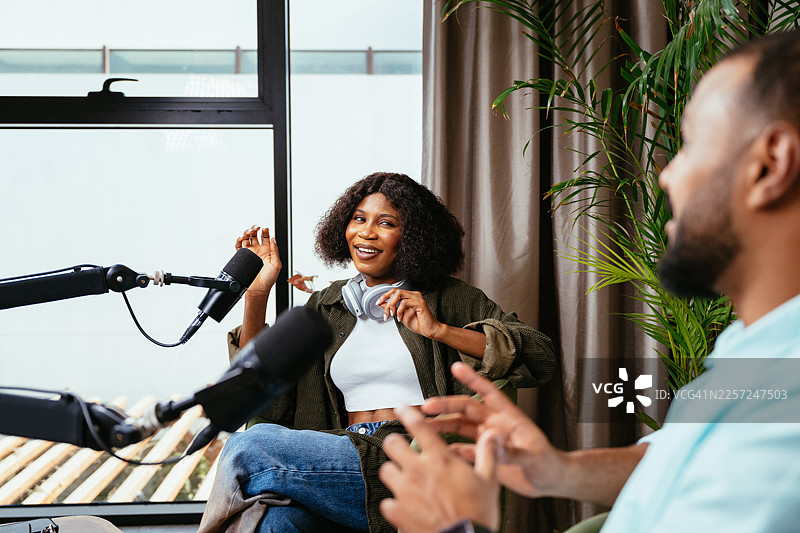 一位女性黑人意见领袖和视频博主在播客录音棚内，正在接受主持人的采访图片素材
