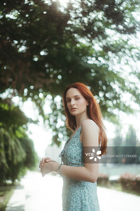 身穿碎花连衣裙的红发女子在户外站立图片素材