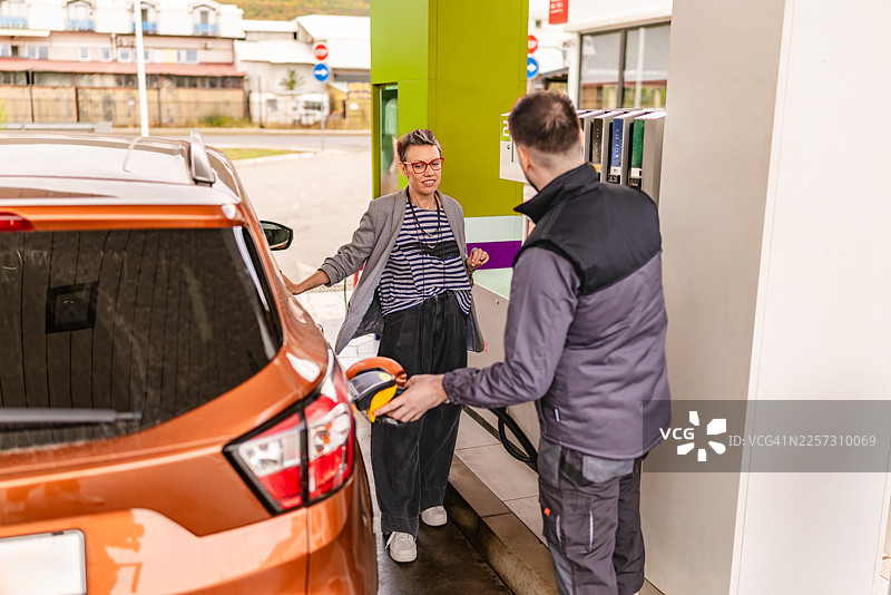 在繁忙的白天，城市区域附近的加油站，顾客正在给汽车加油图片素材