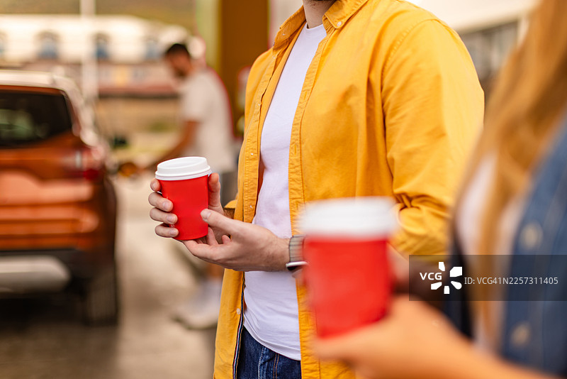 人们在城市里繁忙的一天中，在加油站拿着饮料，为车辆加油图片素材