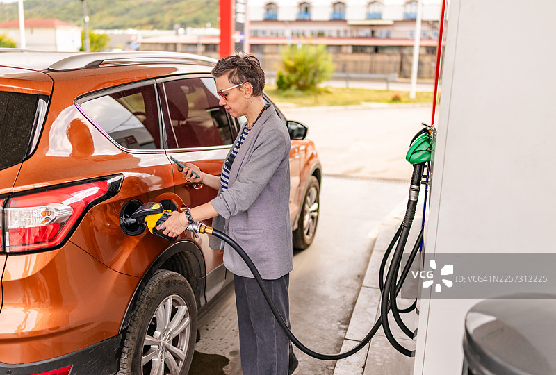 白天在繁忙区域的加油站为汽车加油，有人在操作油泵图片素材