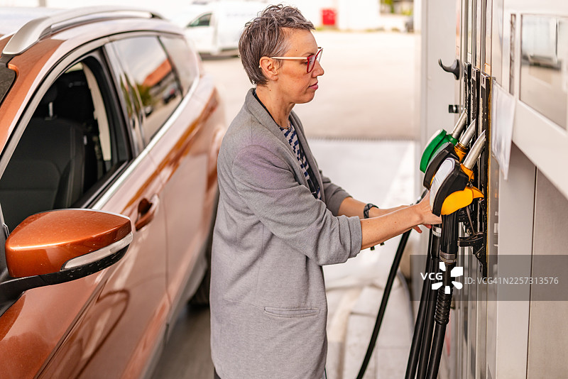 白天在加油站给汽车加油，有人在操作油枪图片素材