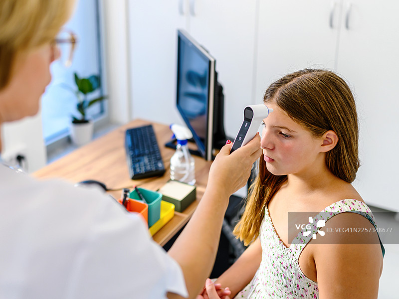 女医生用红外体温计为小女孩测量体温图片素材