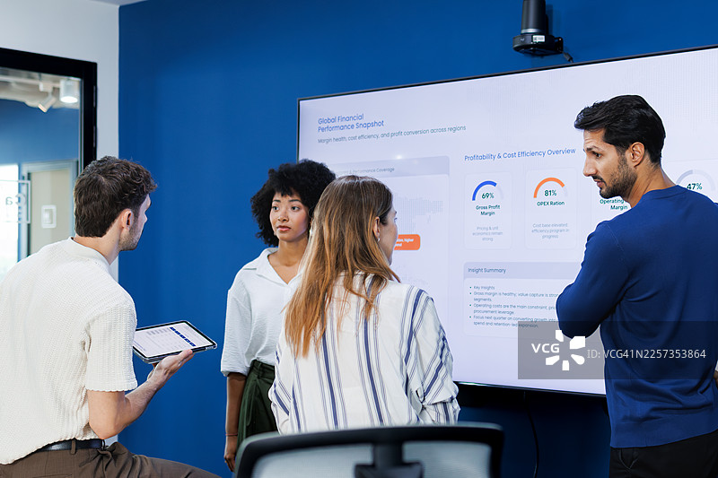 办公室会议室里，同事们正在数字显示屏上分析图表，进行公司战略会议。图片素材