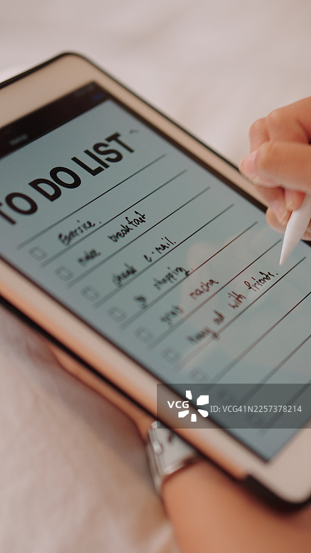 亚洲女性在床上规划她的一天，写下待办事项清单图片素材