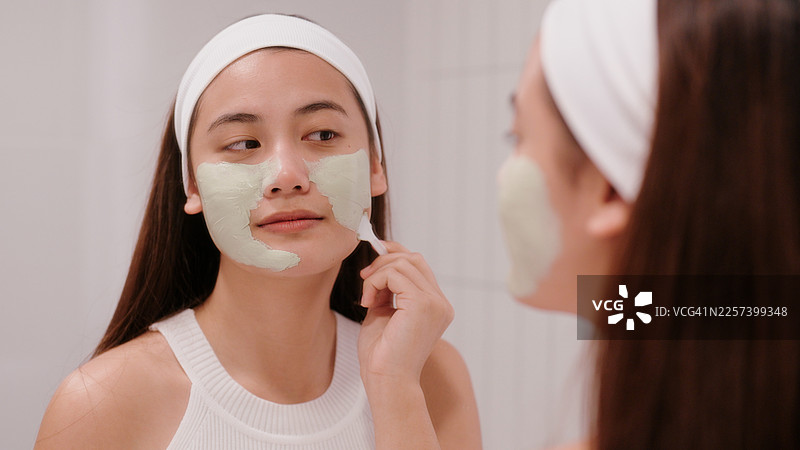 亚洲女性在护肤过程中使用泥状面膜图片素材