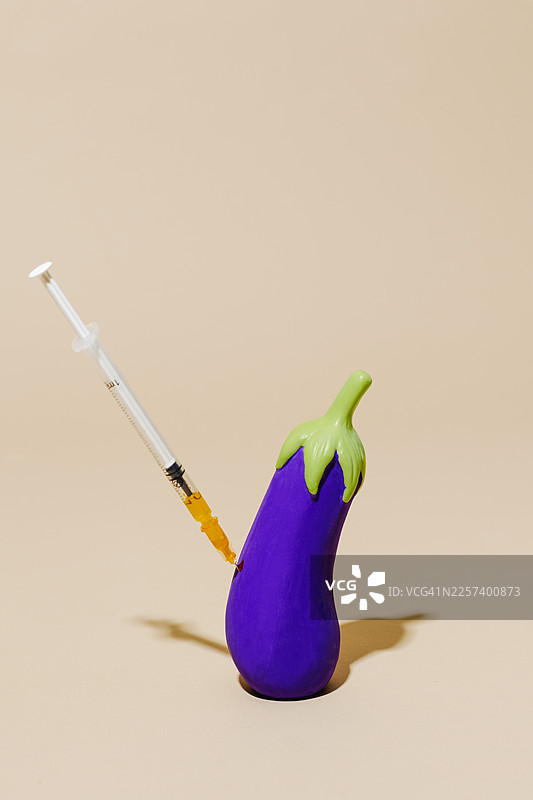 工作室场景中，一个茄子被注射器刺穿图片素材