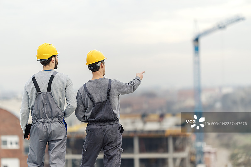建筑工人在建筑工地考察，并指向开发进展图片素材