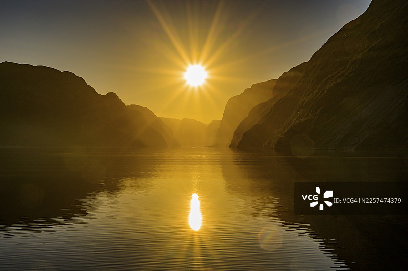 哥伦布渡轮上看到的吕瑟峡湾(Lysefjord)的拉伊瑟峡湾(Laysefjord)宁静水面上,巨大的岩壁之间,倒映着星形的光芒,位于挪威罗加兰郡吕瑟峡湾图片素材