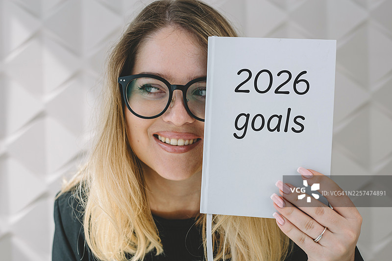 一位微笑的女士拿着写有2026年目标的笔记本图片素材