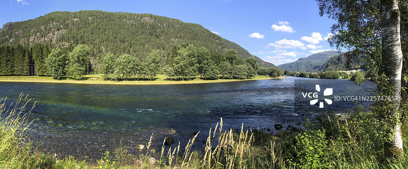 挪威罗加兰桑德，蓝天下，绿树与草地环绕的清澈河流图片素材
