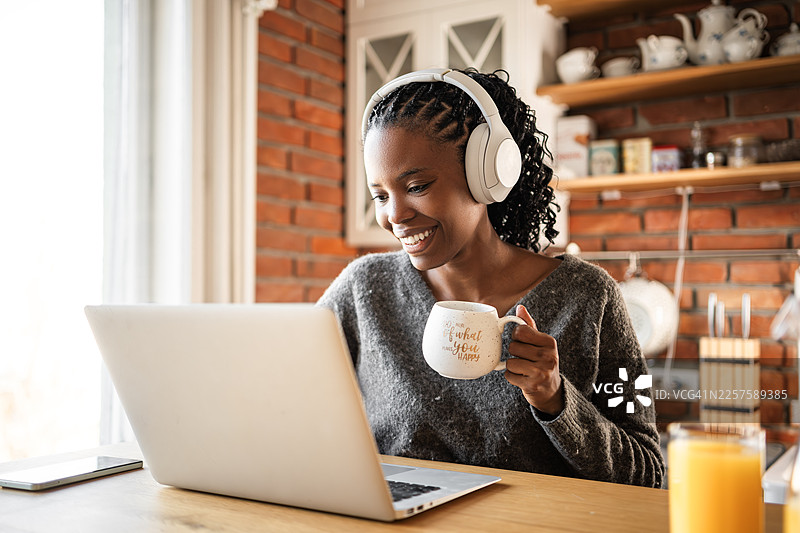 居家办公生活方式，女子使用笔记本电脑和耳机图片素材