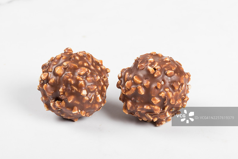 纯素巧克力球，由巧克力制成，裹有切碎的坚果，内馅为坚果奶油和榛子。白色背景。特写。图片素材