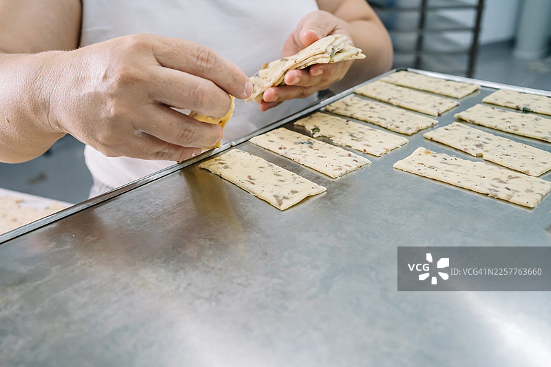 特写一位女性烘焙师将饼干放在烤盘上的手部动作。图片素材