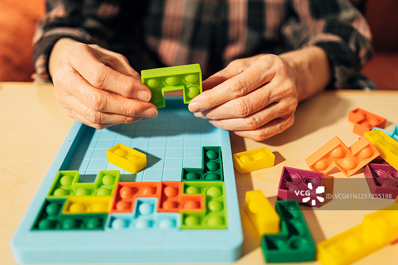 成熟的成年人双手正在摆弄色彩鲜艳的硅胶泡泡乐益智玩具图片素材