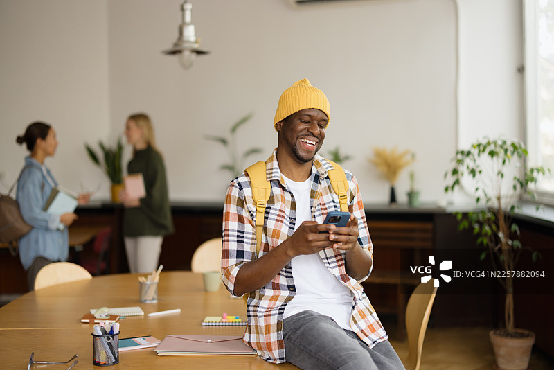 快乐的男学生在图书馆里微笑着使用手机图片素材