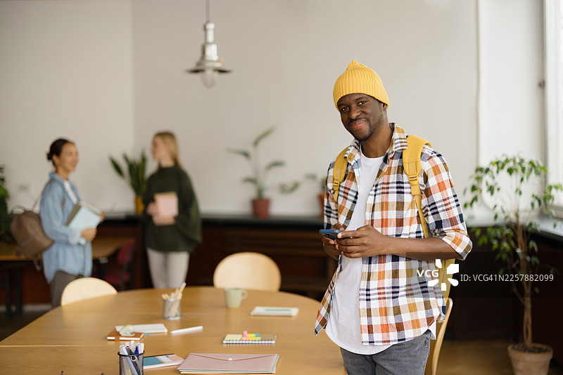 非裔美国学生在校园图书馆里拿着智能手机图片素材