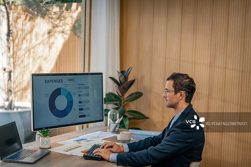 商务人士在现代办公室使用笔记本电脑分析图表图片素材