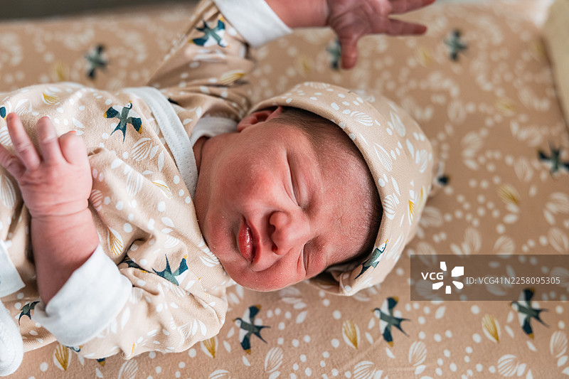 新生儿戴着帽子在医院的床上睡觉图片素材