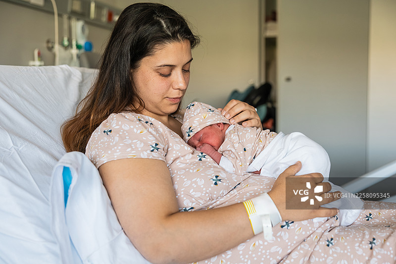 母亲在病床上温柔地抱着新生儿图片素材