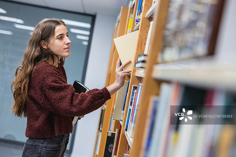 学生在图书馆将书放回书架图片素材