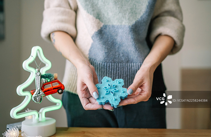 一位女士手持蓝色雪花饼干模具，在家准备圣诞烘焙图片素材