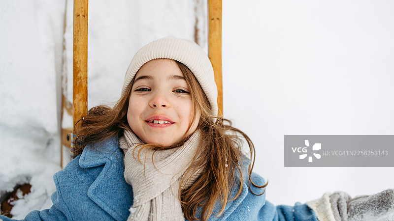 俯视女孩躺在雪橇上，身下是雪图片素材