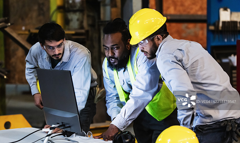 工厂里的工人们正在看电脑显示器图片素材