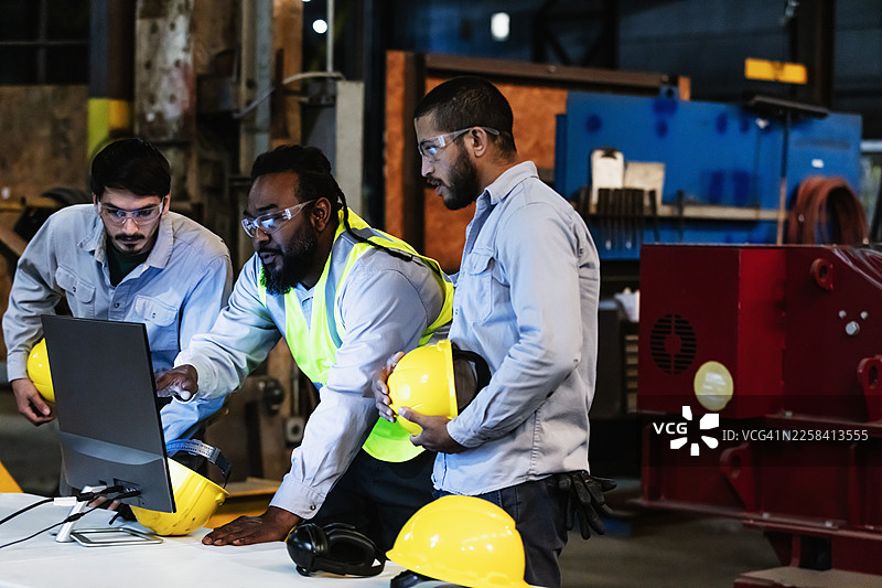 工厂里的工人们正在看电脑显示器图片素材