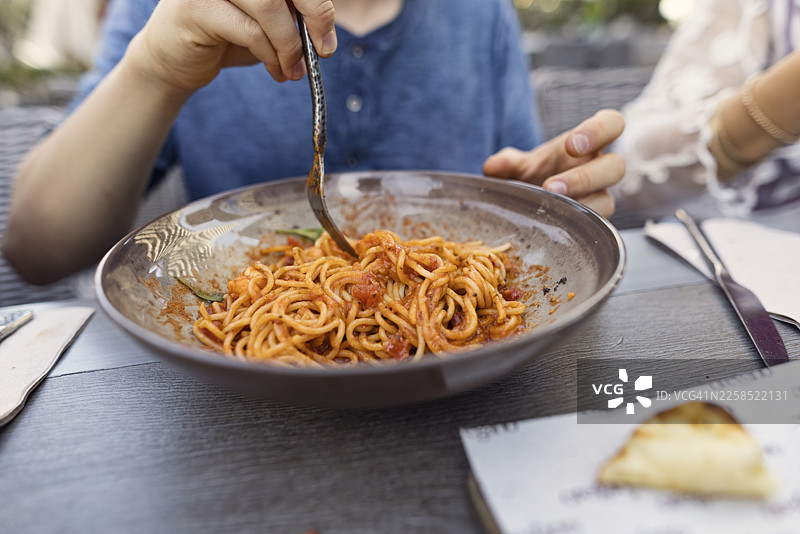 特写：少年在迪拜吃美味的鲜虾意大利面，盘子上沾有番茄酱图片素材