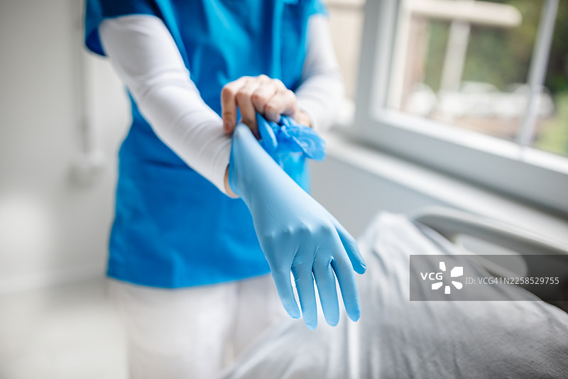 医护人员在病房里戴着蓝色手套，准备协助病人图片素材