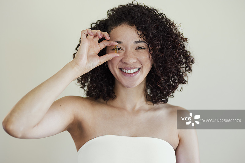 年轻女子开心得将维生素胶囊放在眼睛上方图片素材