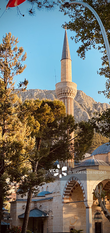 土耳其阿马西亚市中心的清真寺和历史悠久的宣礼塔，拥有传统建筑，背景是湛蓝的天空和群山，绿树环绕。图片素材