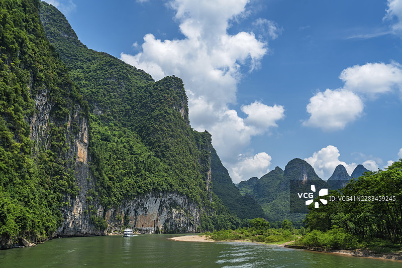 中国桂林与阳朔城镇之间，李河上风景游船载着游客，在壮丽的喀斯特山脉高耸的垂直悬崖间航行图片素材