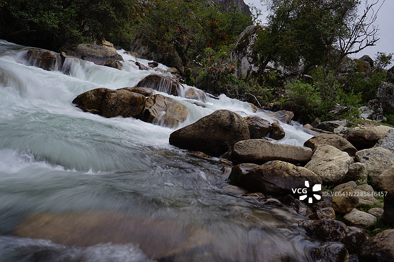 长曝光下的河水流过圆形岩石，位于瓦拉斯图片素材