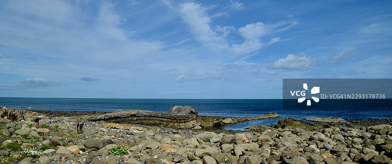 崎岖的海岸线，拥有岩石海滩和平静的蓝色大海，天空中有缕缕的云，阿尔尼克，英国，英国，东北部图片素材