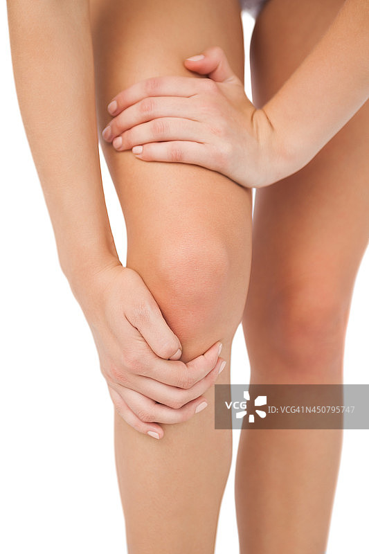 受伤的苗条女子触摸膝盖的特写图片素材