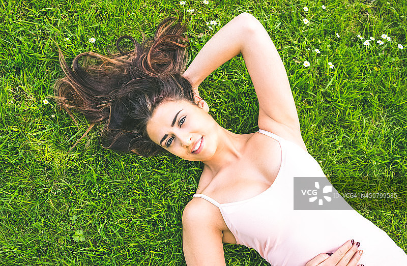 漂亮的棕发女子躺在草坪上图片素材