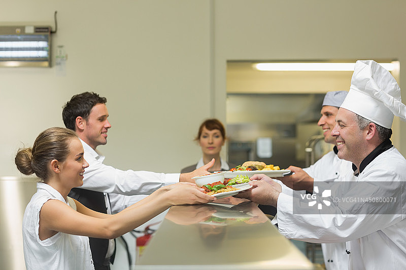 两位厨师将盘子递给服务员图片素材