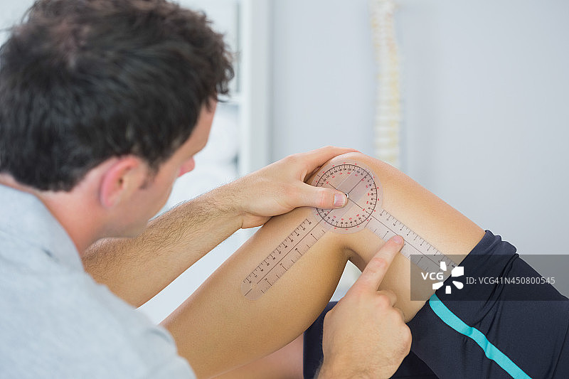 理疗师用测角器检查膝盖图片素材