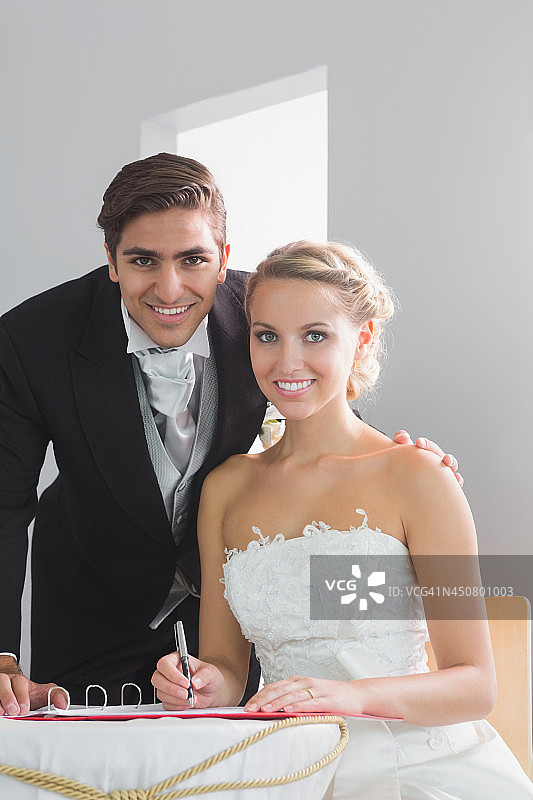 年轻夫妇坐在桌旁签署结婚登记表图片素材