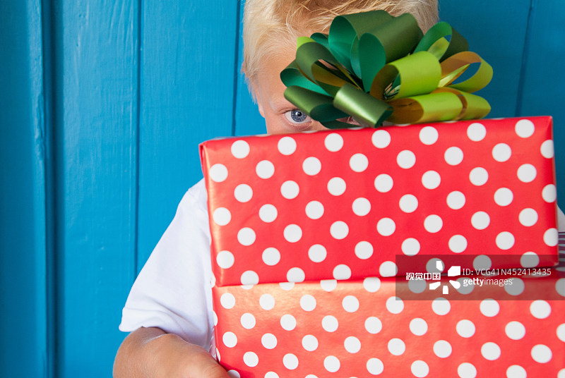 男孩手里拿着礼物在后面偷看图片素材