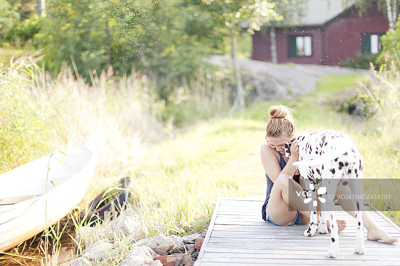 女子在码头上与斑点狗玩耍图片素材